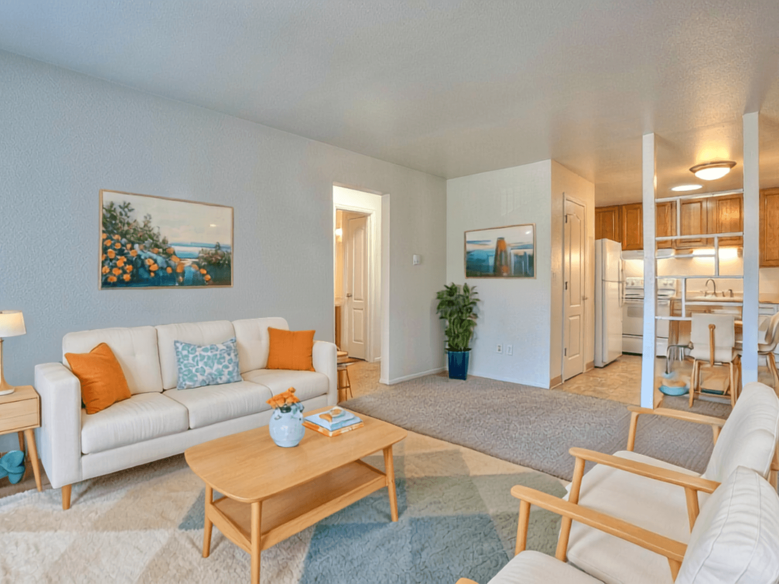 A living room with a white couch, a coffee table, and a painting on the wall.
